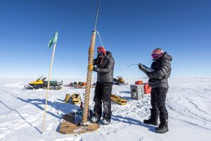 Research Prof. TJ Fudge and student Emma Erwin holding equipment in the field in Antarctica.