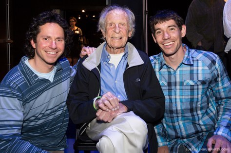 Two younger men sitting with an older man, Fred Beckey, posting for the camera.