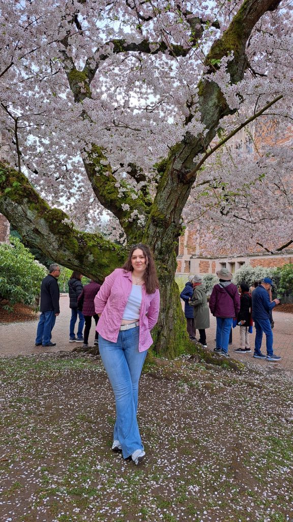 Alyssa Mollnow posing in front of a cherry blossom tree in bloom.