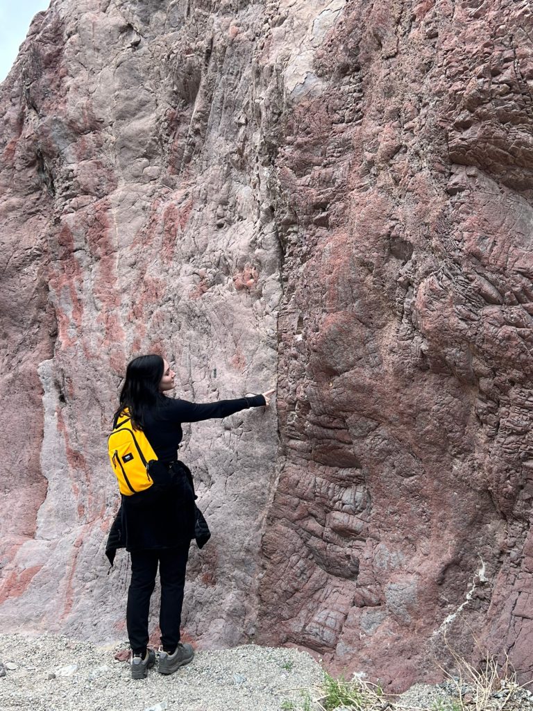 Nicole Lansford standing and pointing at a tall pink rock.