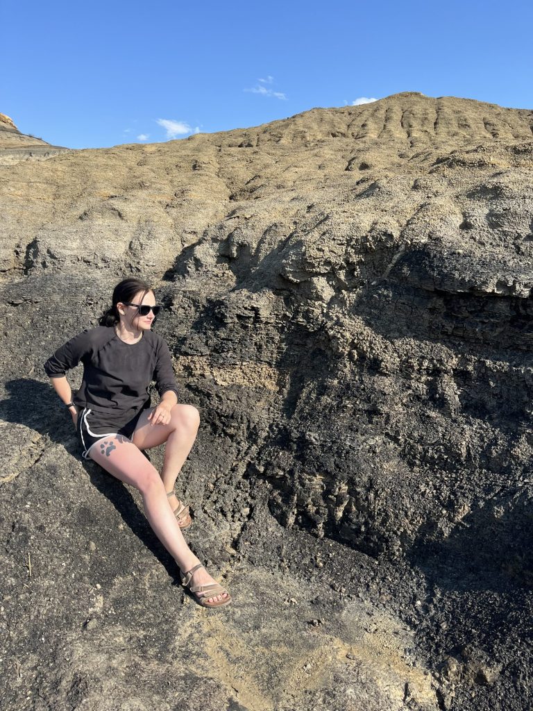 Nicole Lansford sitting on top of a dark gray rock.