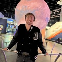 Close up of Nolan English in front of a planet exhibit.