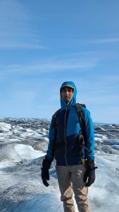 Close up of Vigash Ravi on a glacier with blue sky behind.
