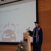 Zachary Adam giving a speech on stage at graduation.