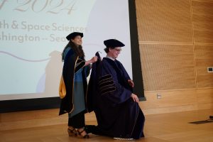 A faculty advisor presenting a graduating graduate student with a hood,