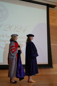 A faculty advisor presenting a graduating graduate student with a hood,
