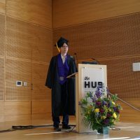 Klay Wu giving a speech on stage at graduation.