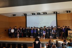 Graduates and faculty standing on stage after graduation.