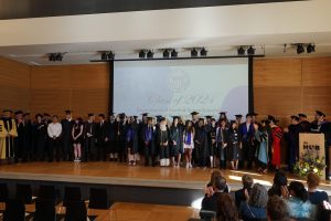 Graduates and faculty standing on stage after graduation.