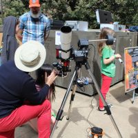 A kid looks through a telescope with Professor Baptiste Journaux to see the sun's surface.