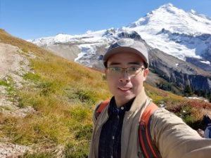 ESS Postdoc Yinbiao Peng taking a selfie in front of a mountain.