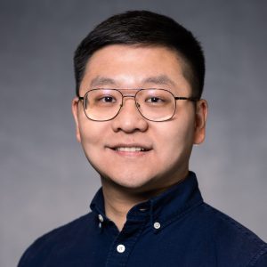 Headshot of Shuai Yan on grey background.