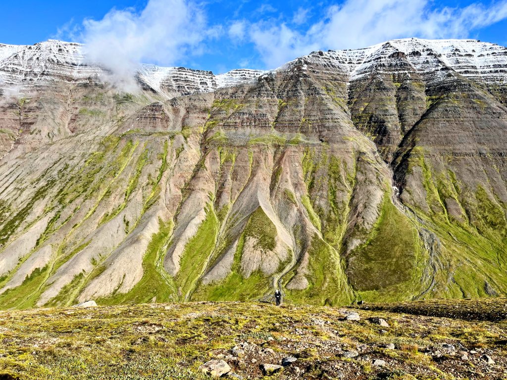Person hiking with alluvial fans and mountains in the background.