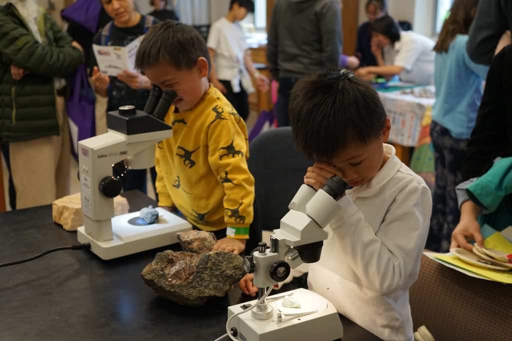 Two kids looking at rocks through microscopes.