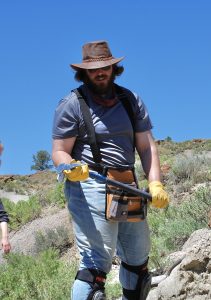 David Ausmus in the field holding a rock hammer.