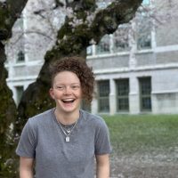 Close up of student Jamie Lutes with a cherry blossom in the background.