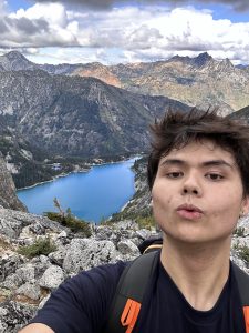 Close up of Isaac Chan with mountain peaks and a mountain lake in the background.