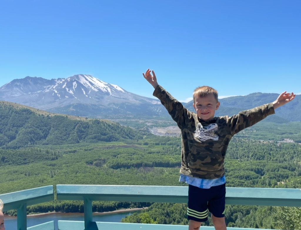 Miles Dimick standing on a platform with Mount St. Helens in the background.