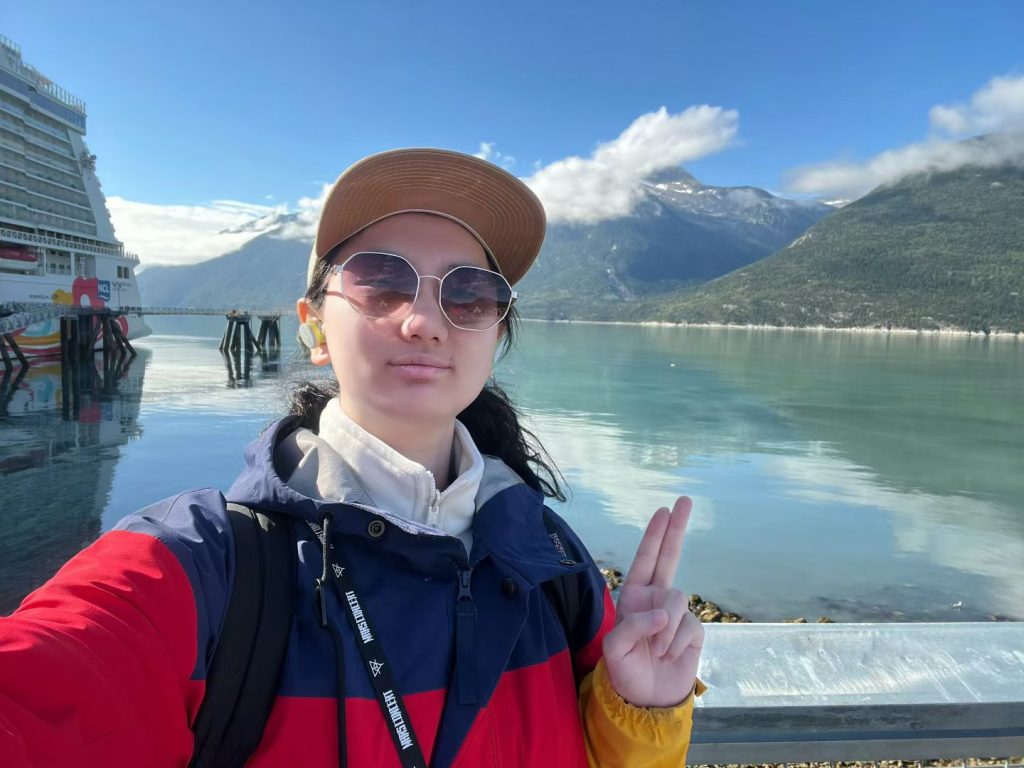 Julia Nie standing in front of a body of water with mountains in the background.