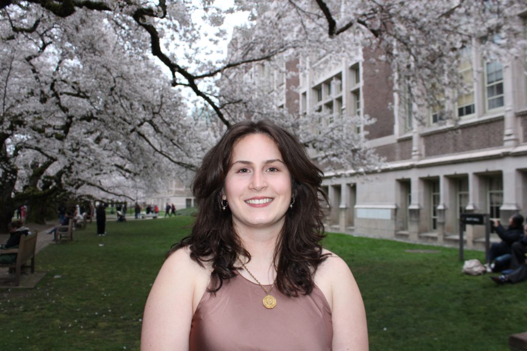Lauren Yoson standing in front of Cherry Blossoms on the UW campus.