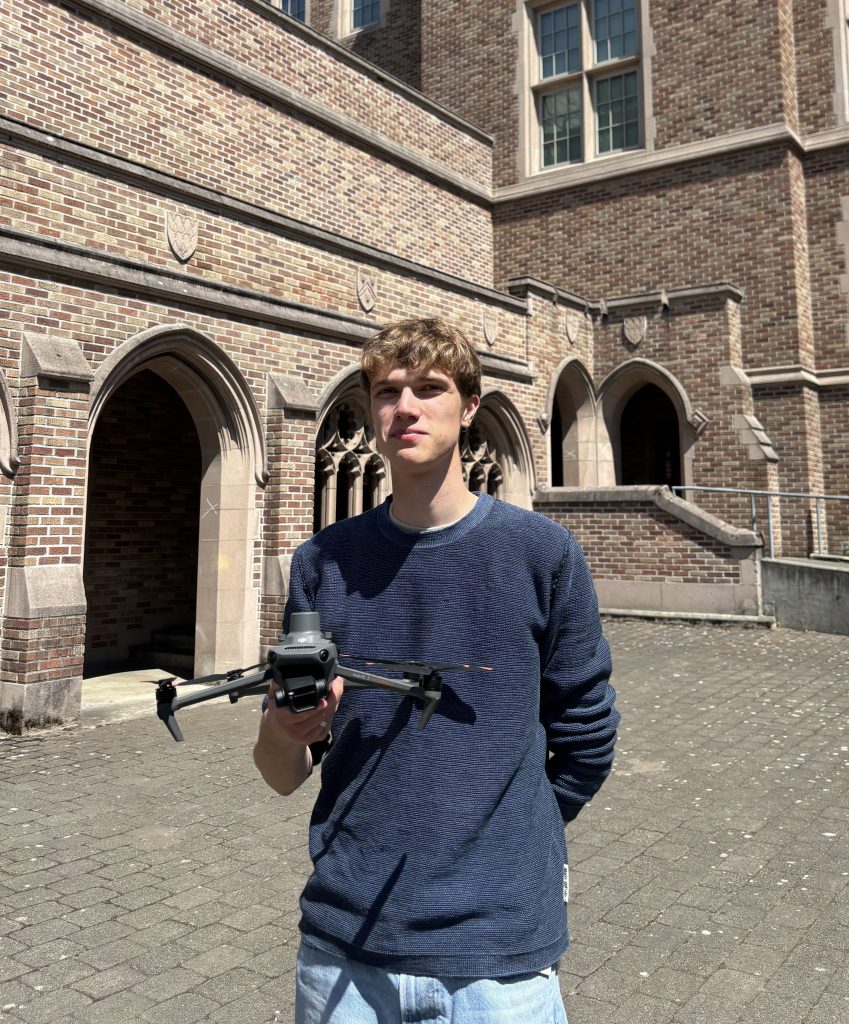 Filip Novak holding a drone standing in the Johnson Hall Courtyard.