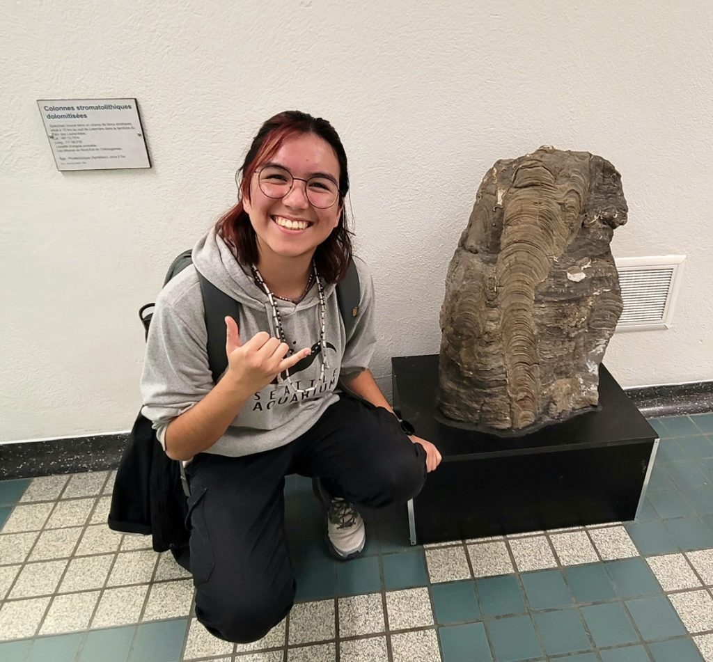 Oli Facq kneeling next to a large fossil.
