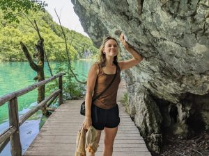 Brielle Herrin leaning against a rock with a lake in the background.