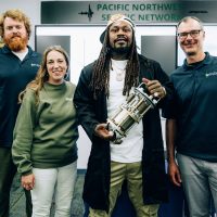 Marshawn Lynch standing with PNSN employees in the PNSN lab.