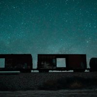Silhouette of a train with stars in the night sky in the background.