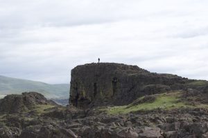 A student standing on top of a large basalt outcrop.