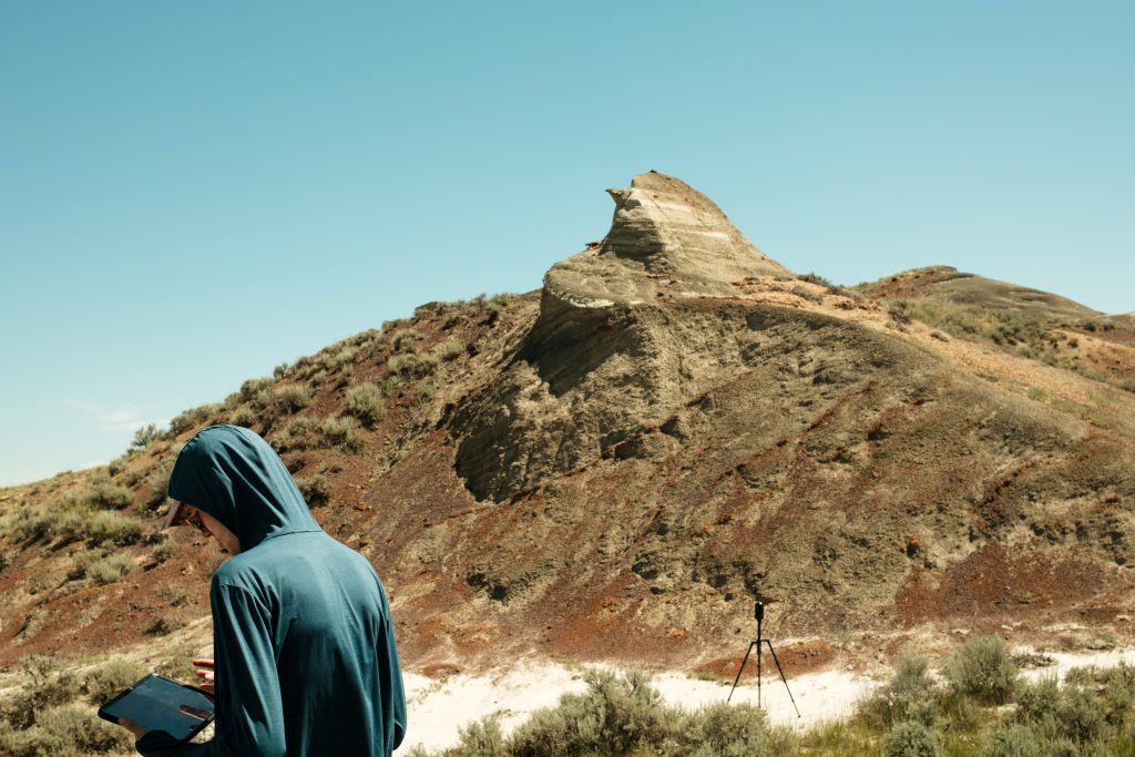 Student Filip Novak standing in front of a large outcrop near Jordan, Montana.