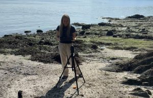 Undergraduate student Jade Wells setting up the LiDAR scanner on a beach.