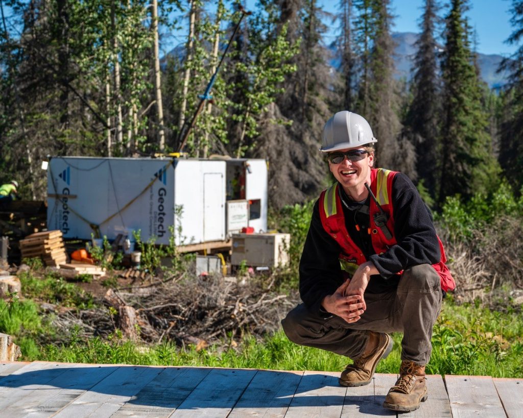 Mick Jordan kneeling in front of a field site in remote Alaska.