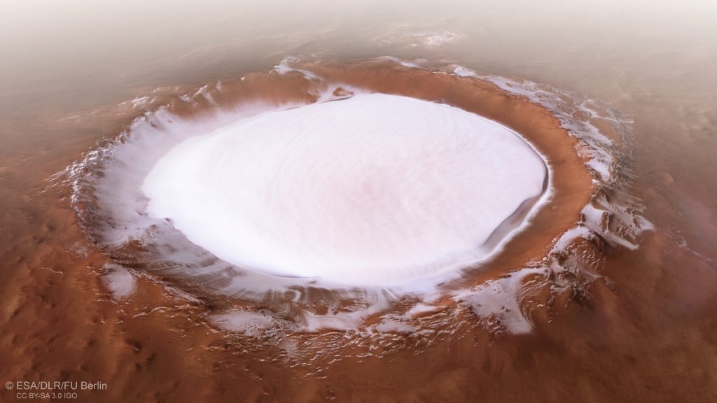 A white circle surrounded by red dust shows exposed ice near the N pole of Mars.